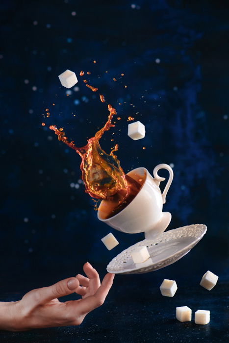 Fun coffee photography shot of a falling cup, saucer and sugar cups balanced on the tip of someones finger