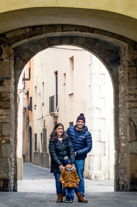 Cute family portrait of a couple with a small baby posing under an arch