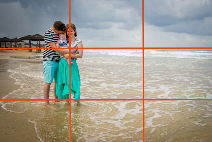 A couple with a small baby posing on a beach with rule of thirds grid line overlayed - family picture ideas