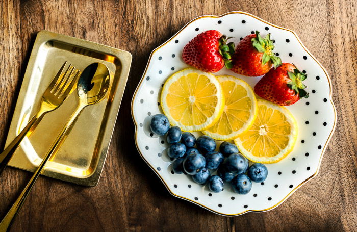 Overhead shot of a luxurious plate of fruits with golden cutlery to be used as photography props for a boudoir shoot