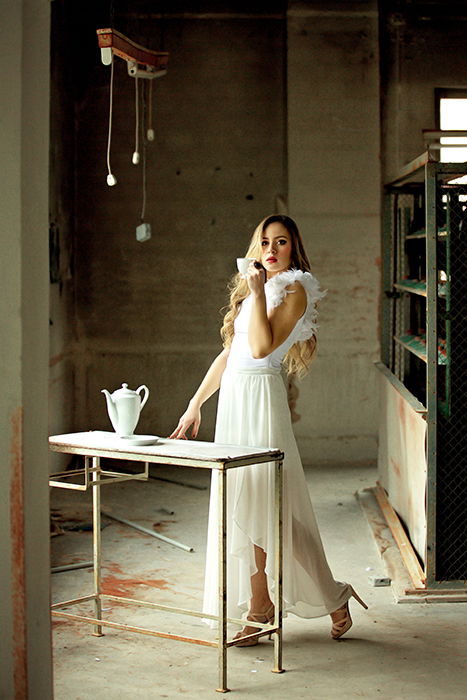 Artistic fine art portrait of a blonde haired female posing in a minimal kitchen area in white evening dress