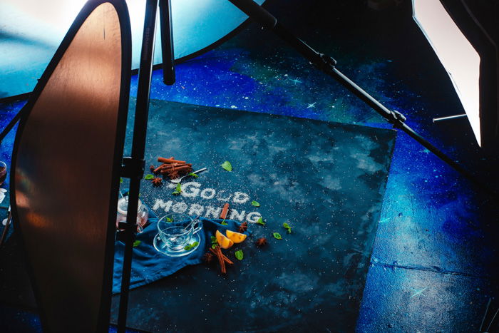 A behind the scene setup of shooting a food art still life with the words 'good morning' created with sugar, fruit and other food typography props