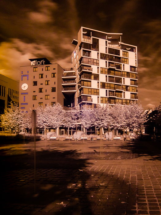 A false color infrared image of the exterior of a large building using tones of orange.