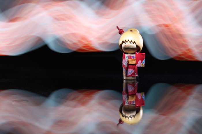 A Japanese wooden doll lit up using a smartphone's flashlight for light painting background