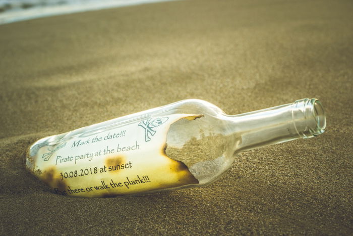 A pirate note inside a bottle in the sand as one of many cool beach photography ideas