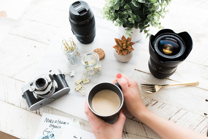 Overhead shot of photography equipment, accessories and coffee cup on a wooden table - camera insurance tips