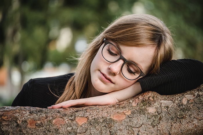 Portrait of a female model resting on a tree with a natural blurry portrait background