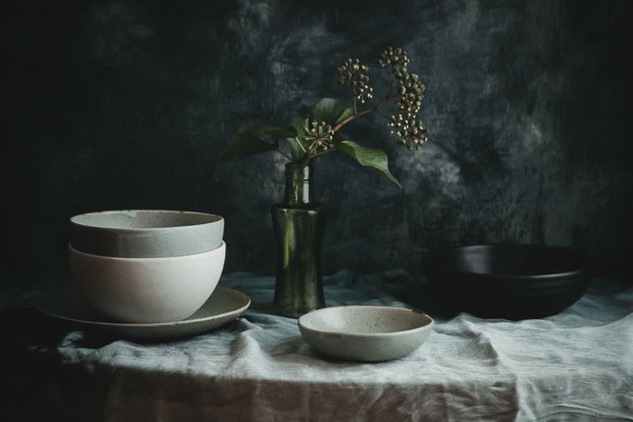 Still life of pottery bowls on a table against dark background - product photography tips