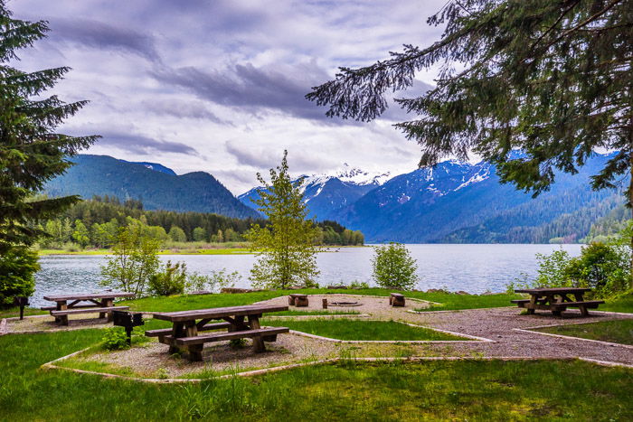 A campground picnic area with lake and mountains in the background