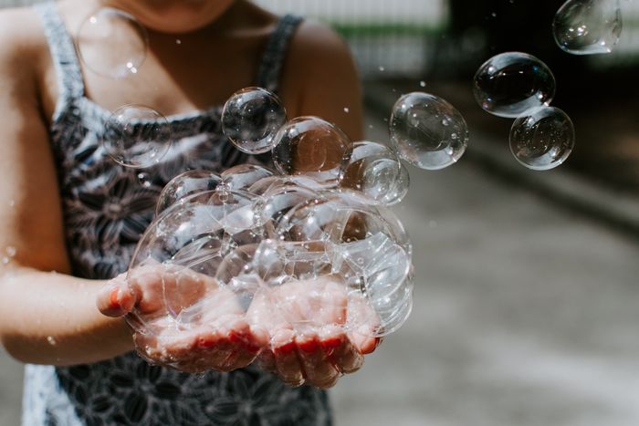 photo of a girl holding soap bubbles in her hands