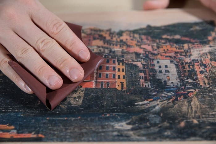 Close up of sanding the photo transfer on the wooden board - how to transfer laser print to wood