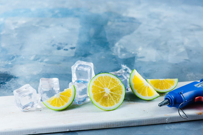 Set up for water splash photography with acrylic ice cubes, limes and glue gun