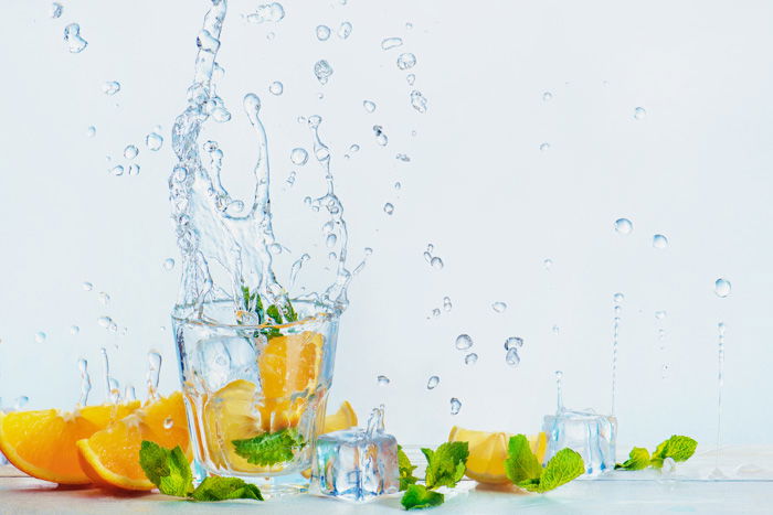 a creative food photography set up with oranges and water splashes on white background