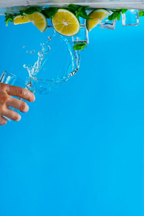 Upside down shot of poruring water onto a still life on blue background