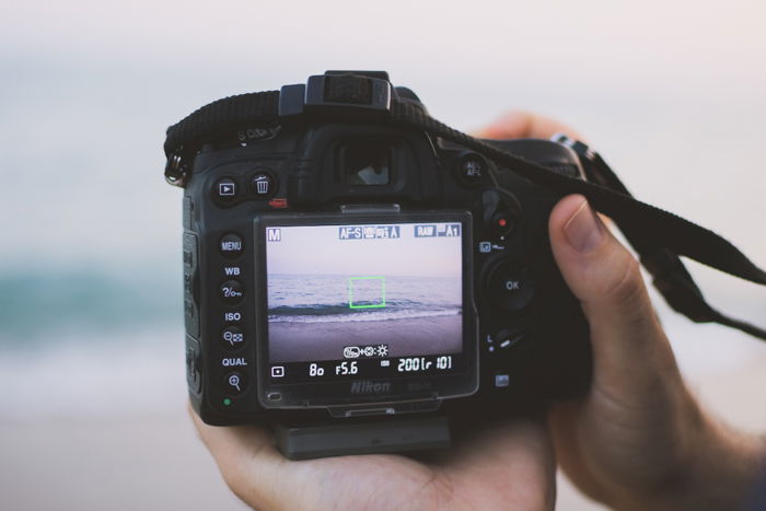 Close up of a person taking a photo of a seascape with a DSLR camera 