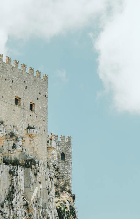 A photo of the exterior of a stone castle against a cloudy blue sky