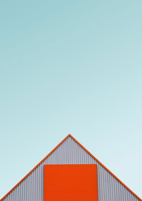 A photo of the orange roof of a warehouse or shed against a teal sky 