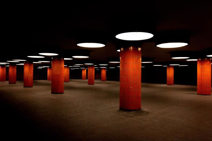 A photo of the interior facade of a dark room with many red columns