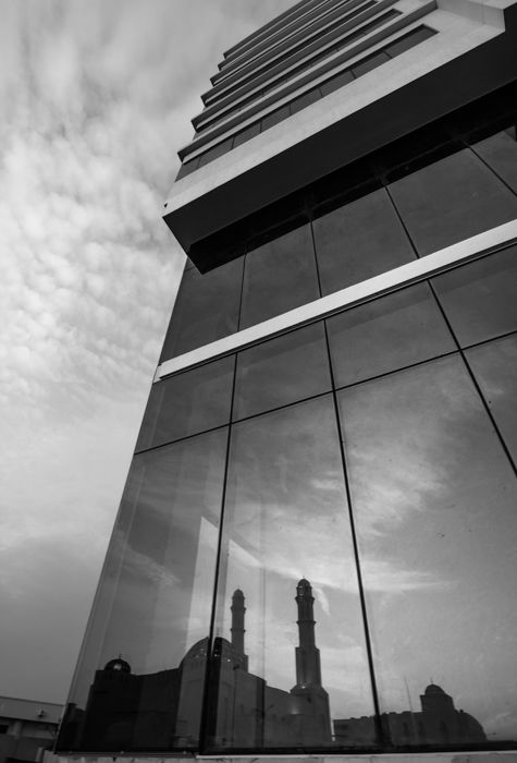 A buildings silhouette reflected in the glass facade of another building -- architecture photography composition