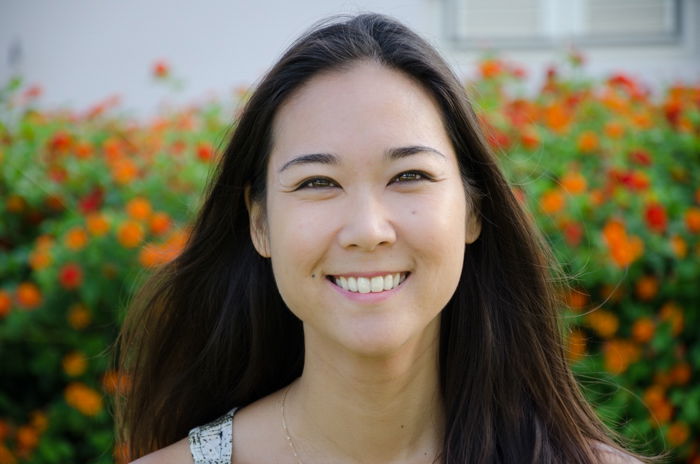 Headshot of smiling asian woman in a field of red flowers