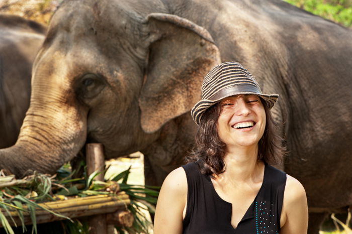 European woman tourist enjoys being with elepants on National Elephant Day in Thailand where they are treated to a huge feast.