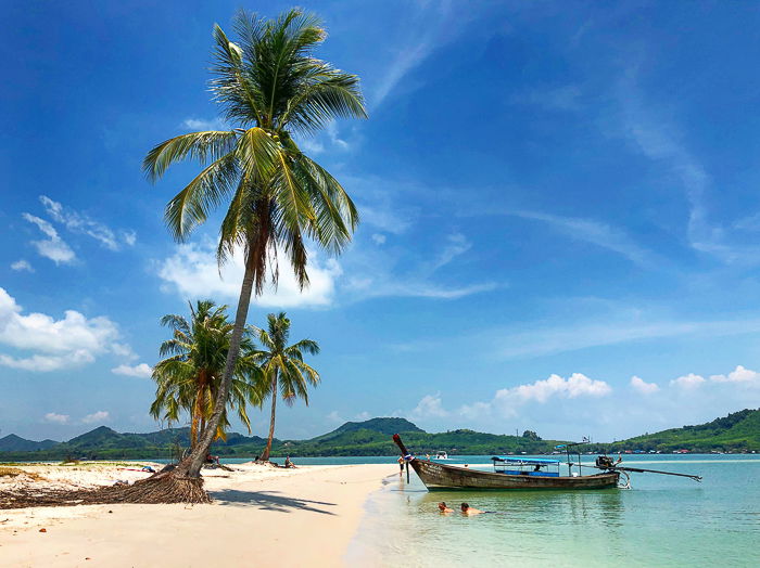 A dreamy tropical beach scene with palm trees and wooden boat 