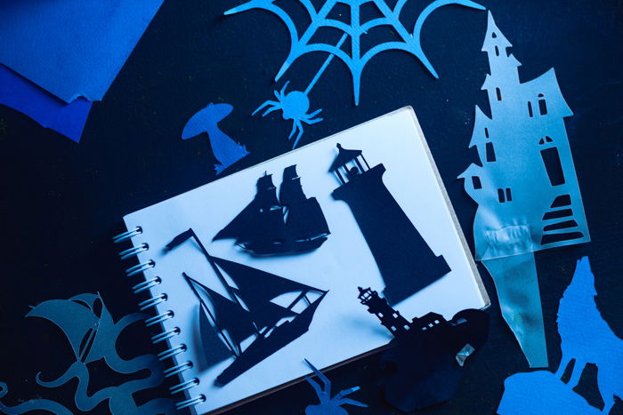 A variety of paper cut silhouettes on a white notebook page