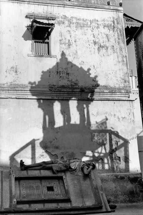 a henri cartier-bresson photo of a man lying outside a building