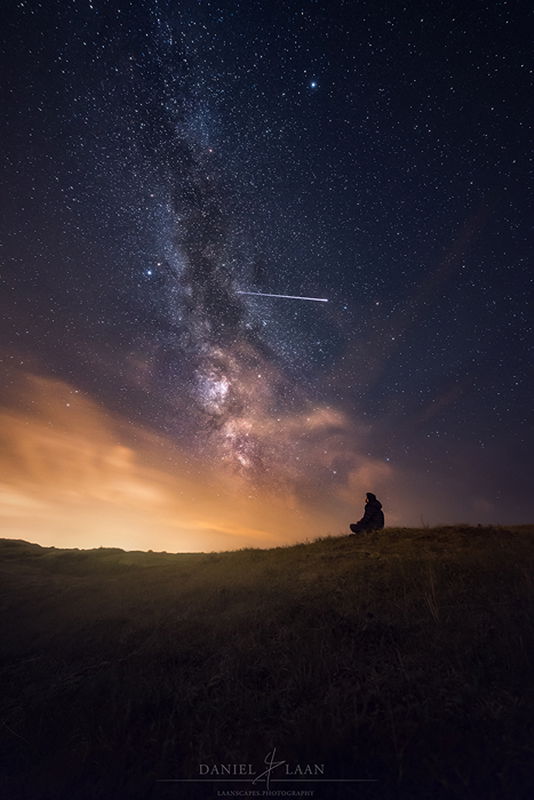 Stunning shot of ISS passing overhead while a man sits and gazes at the stunning star filled sky above