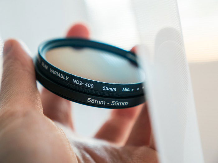 A hand holding an ND filter for landscape photography