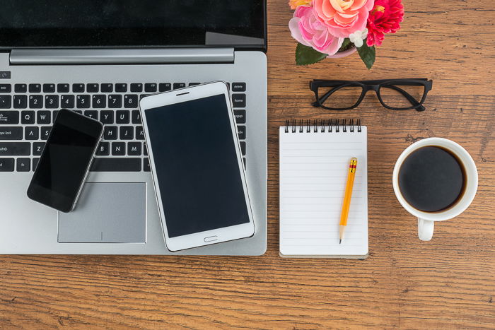 Overhead shot of a laptop, phone, tablet and notebook - preparing for submitting photos