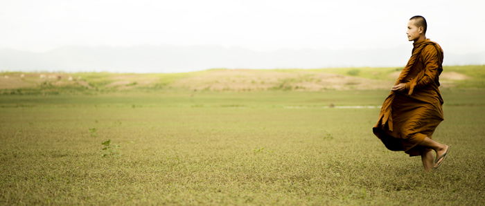 bright and airy cinematic photography portrait of a monk in a green field