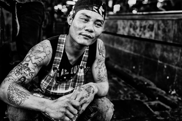 A black and white portrait of a Thai butcher kneeling on the ground - photography contrast