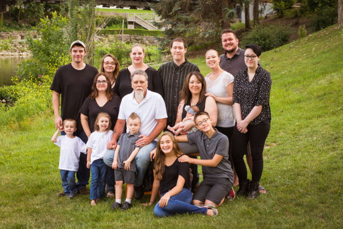 Several generations in a family photo, posing at the foot of a grassy hill on an overcast day