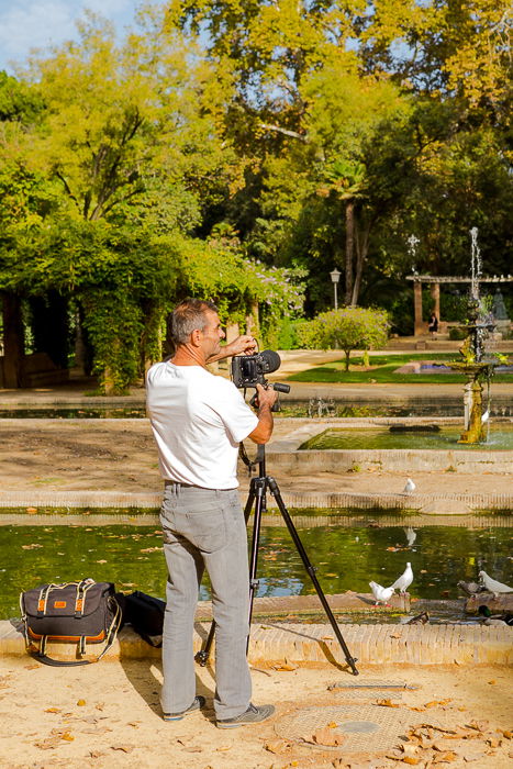 photo of a man at the lake shore, setting up his camera on a tripod