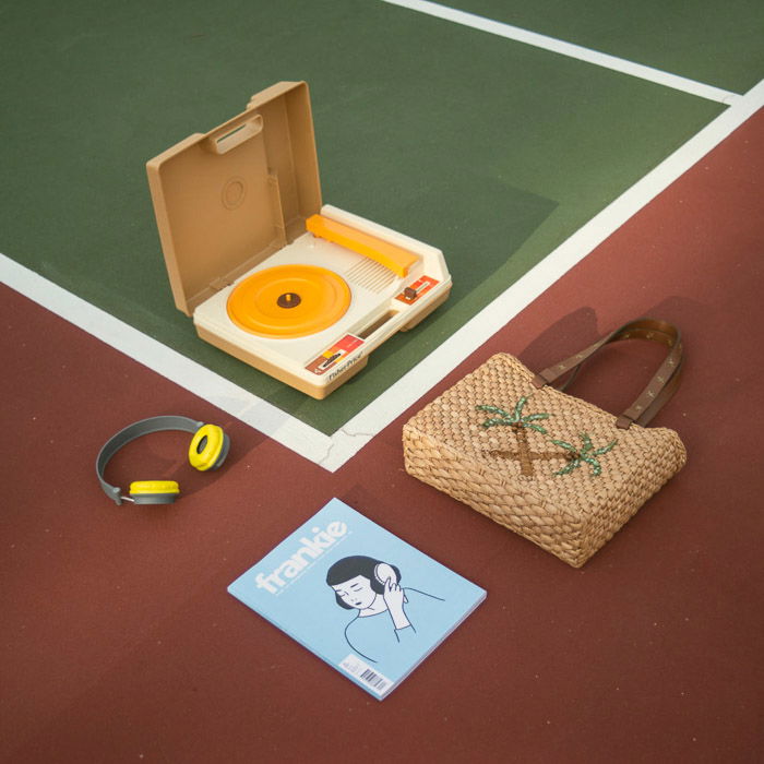 Overhead shot of a record player, bag, magazine and earphones laid out on a sports track