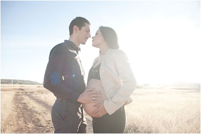 A romantic photo of pregnant couple outdoors, the bright sun behind them