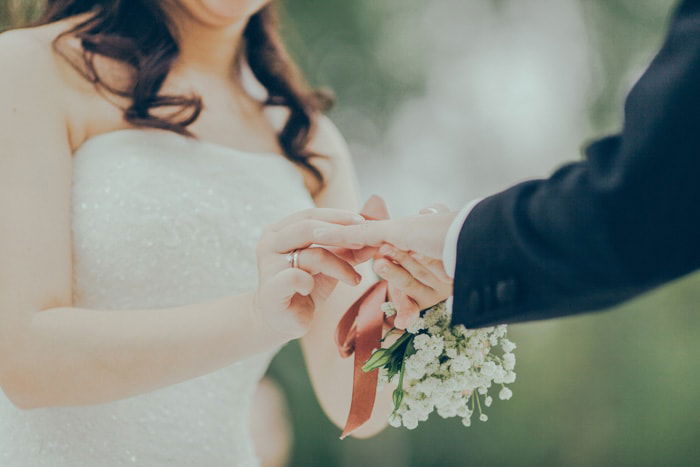 Dreamy close up wedding portrait of a bride placing a ring on the grooms finger 