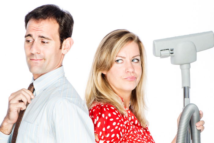 A studio portrait of a couple dispute who should do the cleaning using household appliances as photography props