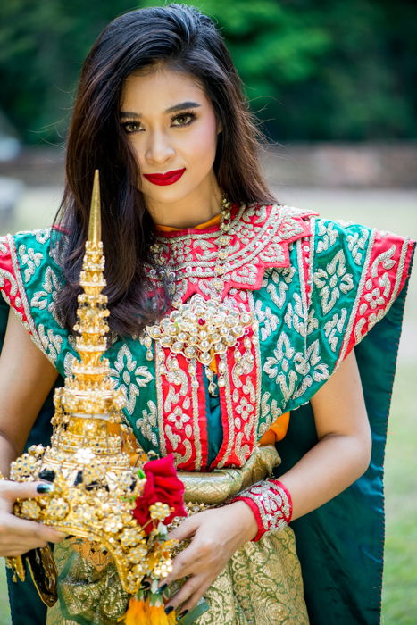 A beautiful female model in Classical Thai costume holding photography props for extra impact