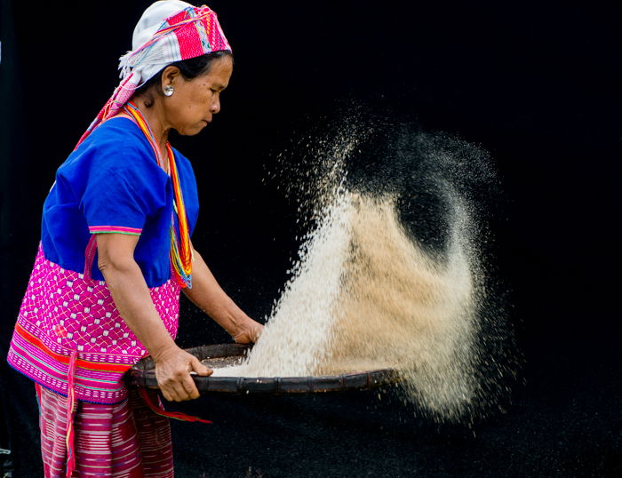 A woman holdoing a tray full of rice against a dark portrait background - using photography props 