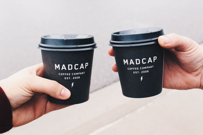 two hands holding black take out coffee cups