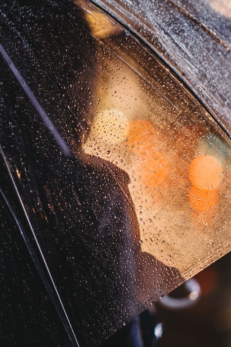 Abstract portrait of a person under a rain-splatted umbrella with bokeh light shining in the background