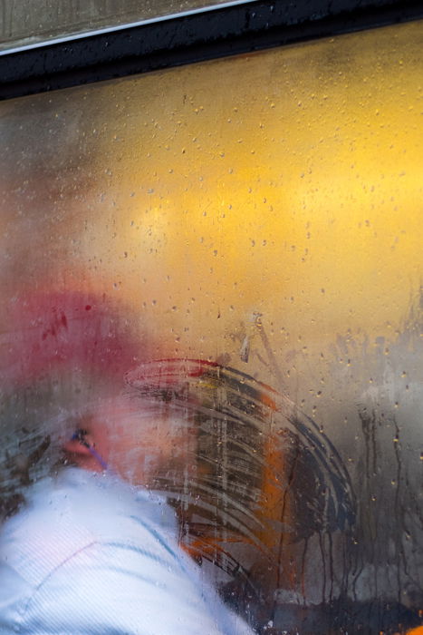 A portrait of a person shot through a rain splashed window