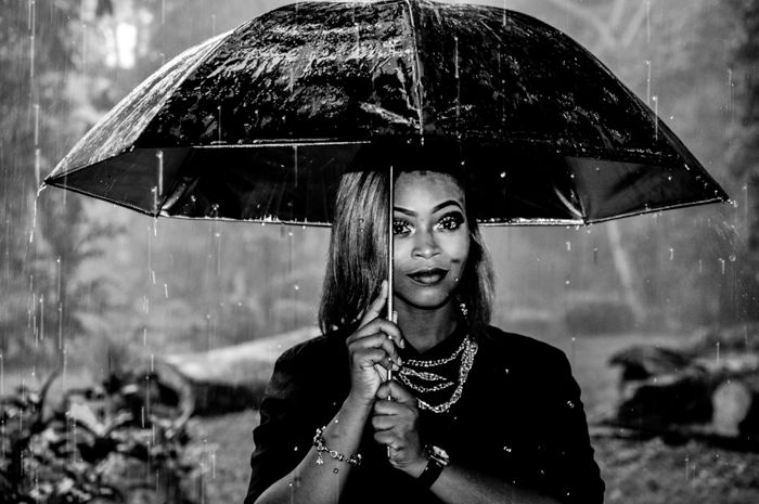 Black-and-white portrait of a woman holding an umbrella in the rain