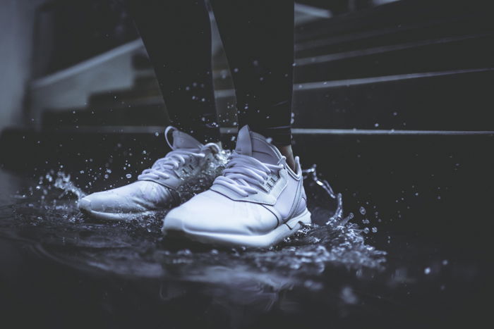 Dark and moody rain image of a person's feet stomping in a puddle shot with fast shutter speed