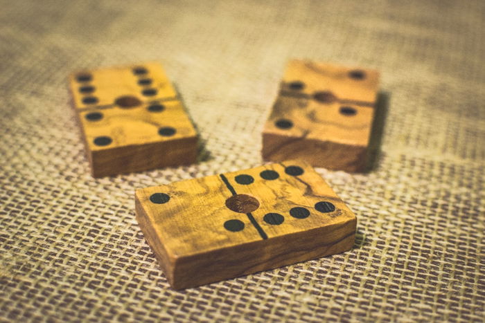 close up of three wooden domino tiles on a brown table using rule of odds composition