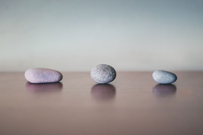 three grey stones on wood surface