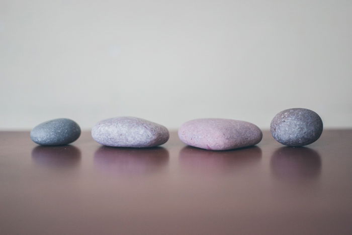 four grey stones lined up on a wooden surface