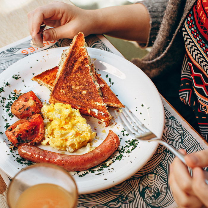 A smartphone food photography shot of a person eating a scrumptious looking brunch at a table